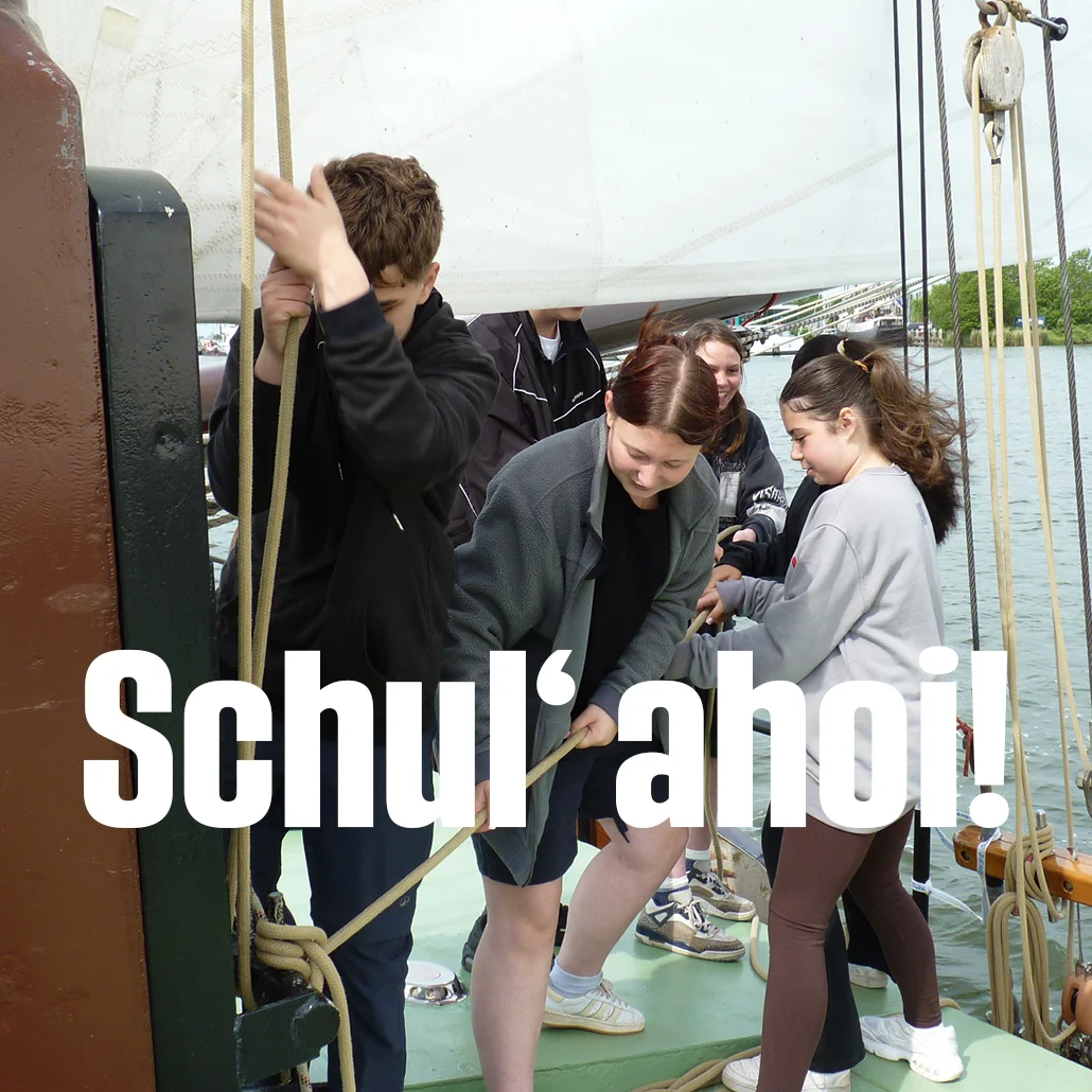 Mehrere Jugendliche an Deck eines Segelschiffs, die gemeinsam Taue ziehen und Segel bedienen.